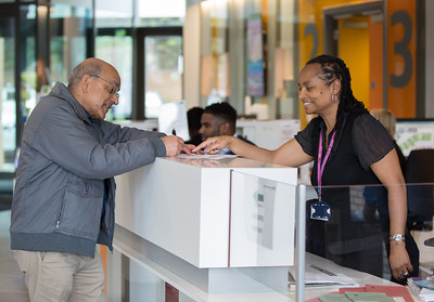 A Healthwatch volunteer speaks with a service user in a hospital reception area