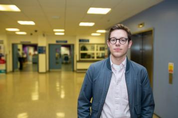 Young man standing face on to camera in a hospital hallway