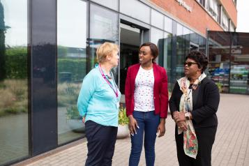 Three women standing outside a hospital talking