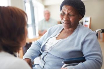 Black elderly woman ina nursing home being spoken to by a nurse