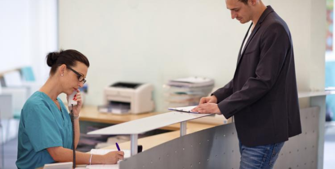 Female receptionist talking on the phone while patient waits